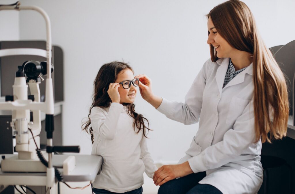 A child trying on glasses during a visit with an eye doctor