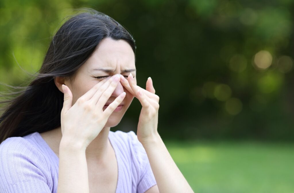 Young person rubbing her eyes while outside