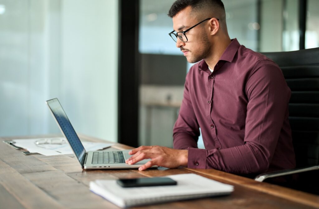 A person using a computer for work while they wear glasses